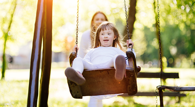 Developmentally disabled girl on a swing in a park.